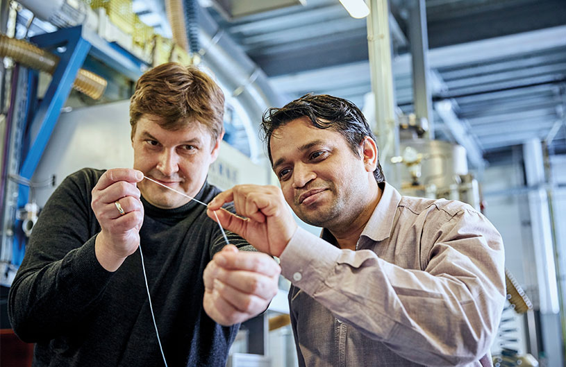 Scientists holding a synthetic fiber prototype made
