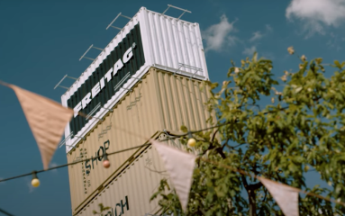 Stacked shipping containers with the logo of Freitag on top (graphic)